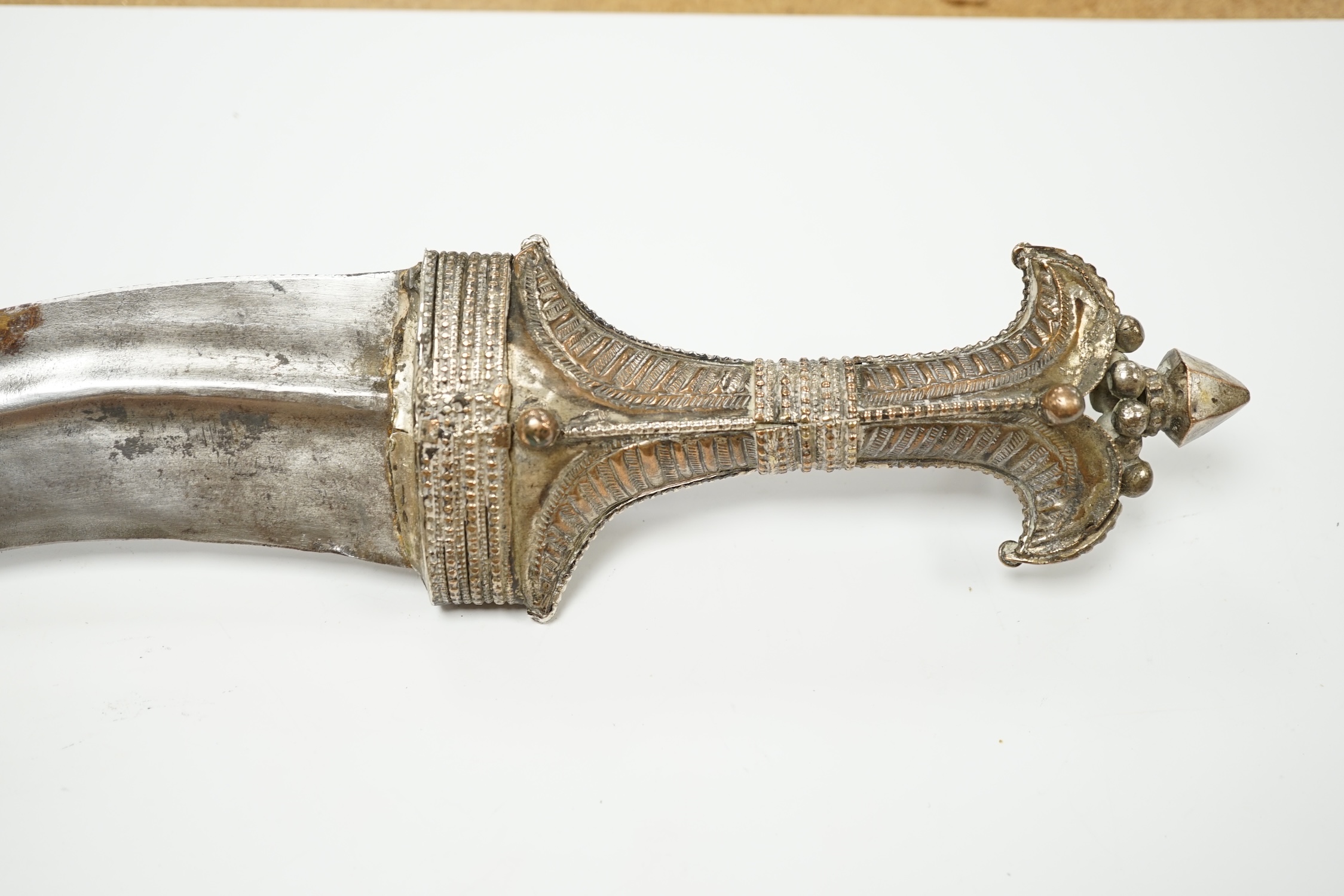 A composite Saudi dagger Jambiya c.1900, silver plated hilt, silver coloured metal sheath with engraved decoration. Condition - good, some wear